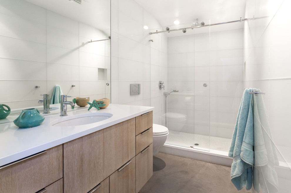 Inspiration för små moderna en-suite badrum, med släta luckor, skåp i ljust trä, en dusch i en alkov, en vägghängd toalettstol, vit kakel, glaskakel, vita väggar, betonggolv, ett undermonterad handfat och bänkskiva i kvarts