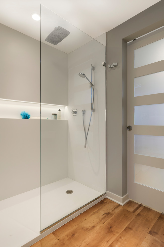 Photo of a small modern shower room bathroom in Minneapolis with brown cabinets, a built-in shower, a one-piece toilet, white tiles, grey walls, vinyl flooring, a wall-mounted sink, brown floors, an open shower and white worktops.