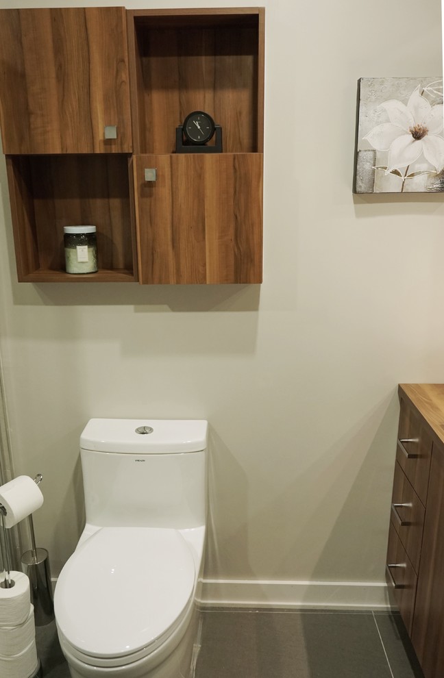 Cette image montre une salle de bain principale design en bois brun de taille moyenne avec un placard à porte plane, WC à poser, un carrelage gris, une baignoire indépendante, une douche d'angle, des carreaux de porcelaine, un mur gris, un sol en carrelage de céramique, un lavabo posé, un plan de toilette en stratifié, un sol gris, une cabine de douche à porte battante, un plan de toilette marron, meuble simple vasque et meuble-lavabo sur pied.