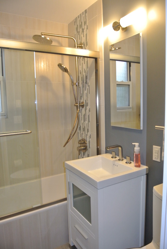 Imagen de cuarto de baño actual de tamaño medio con puertas de armario blancas, bañera empotrada, lavabo integrado, armarios tipo vitrina, combinación de ducha y bañera, sanitario de dos piezas y paredes azules
