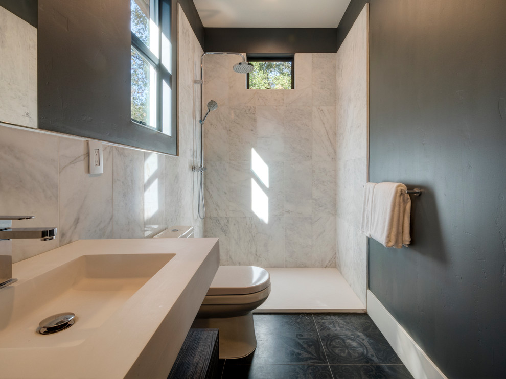 Ispirazione per una stanza da bagno con doccia di medie dimensioni con WC monopezzo, piastrelle nere, piastrelle in gres porcellanato, pareti bianche, pavimento in gres porcellanato, lavabo sospeso e top in superficie solida