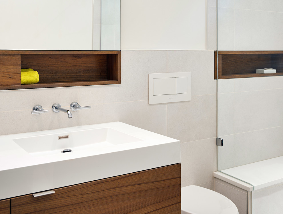 This is an example of a small modern ensuite bathroom in Baltimore with flat-panel cabinets, brown cabinets, a built-in shower, a wall mounted toilet, yellow tiles, porcelain tiles, white walls, porcelain flooring, an integrated sink, solid surface worktops, grey floors and a hinged door.