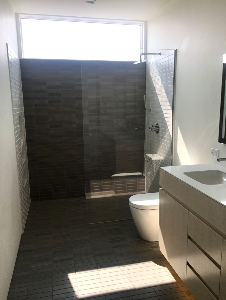 Пример оригинального дизайна: детская ванная комната среднего размера в стиле модернизм с плоскими фасадами, белыми фасадами, душем без бортиков, унитазом-моноблоком, белой плиткой, керамической плиткой, белыми стенами, полом из керамической плитки, врезной раковиной, столешницей из искусственного кварца, черным полом, открытым душем, белой столешницей, нишей, тумбой под две раковины и подвесной тумбой