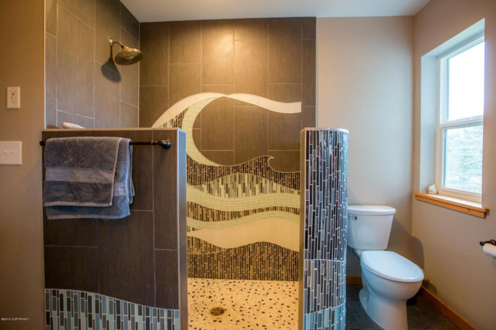 Lantlig inredning av ett stort badrum med dusch, med ett badkar i en alkov, en öppen dusch, en toalettstol med hel cisternkåpa, flerfärgad kakel, glaskakel, beige väggar, skiffergolv, grått golv och med dusch som är öppen