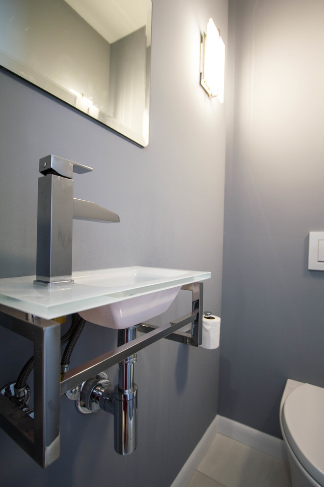 Réalisation d'un WC suspendu minimaliste de taille moyenne avec un mur gris, un sol en carrelage de porcelaine, un lavabo intégré, un plan de toilette en verre et un sol blanc.