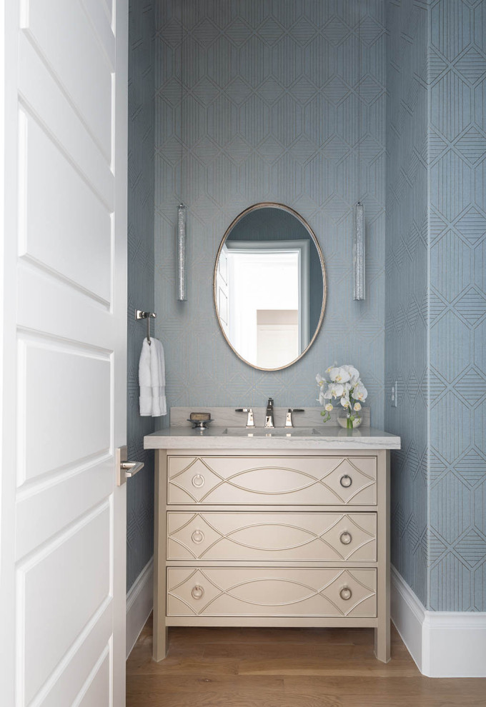 Diseño de cuarto de baño único y de pie clásico renovado con puertas de armario beige, paredes azules, suelo de madera en tonos medios, suelo marrón, encimeras beige y papel pintado
