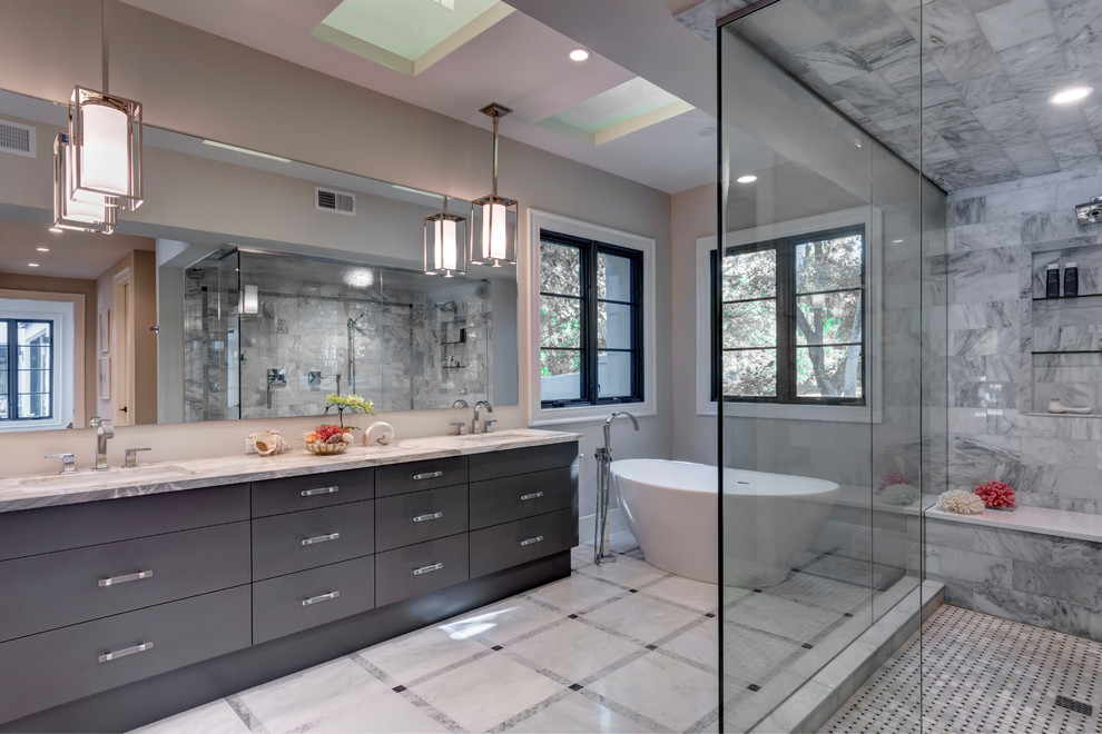 Aménagement d'une grande salle de bain principale moderne en bois foncé avec un placard à porte plane, une baignoire indépendante, une douche d'angle, un mur beige, un lavabo encastré, un plan de toilette en marbre, un carrelage de pierre et un sol en marbre.