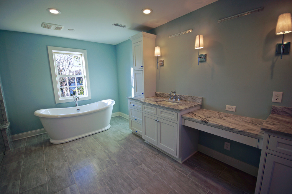 Photo of a large traditional ensuite bathroom in Cincinnati with recessed-panel cabinets, white cabinets, a freestanding bath, a corner shower, blue walls, laminate floors, a submerged sink, quartz worktops, grey floors, an open shower and grey worktops.