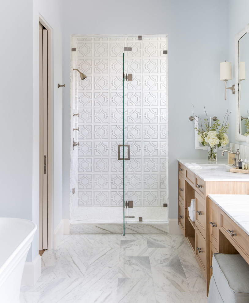 Réalisation d'une salle de bain tradition en bois clair avec un placard avec porte à panneau encastré, une baignoire indépendante, un carrelage blanc, un mur gris, un lavabo encastré, un sol blanc et un plan de toilette blanc.