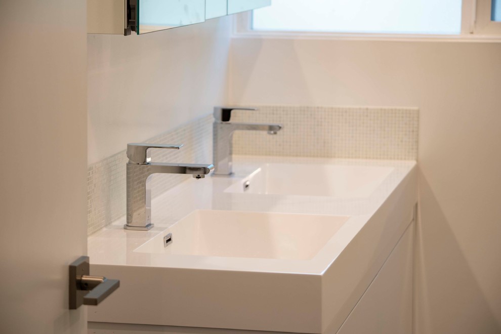 This is an example of a small modern family bathroom in Other with freestanding cabinets, white cabinets, a corner shower, a two-piece toilet, white tiles, glass sheet walls, white walls, porcelain flooring, an integrated sink, quartz worktops, black floors, a hinged door and white worktops.