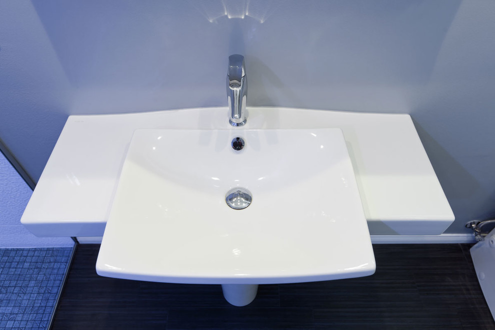 Ejemplo de cuarto de baño moderno con lavabo con pedestal, paredes azules y suelo de baldosas de porcelana