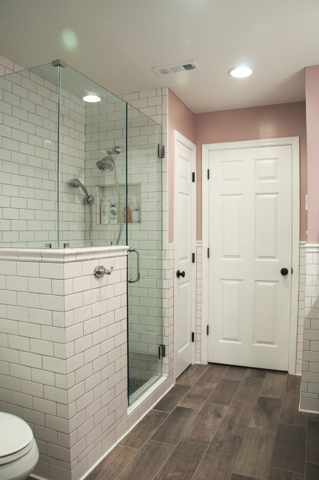 На фото: главная ванная комната среднего размера в викторианском стиле с врезной раковиной, фасадами в стиле шейкер, темными деревянными фасадами, столешницей из гранита, отдельно стоящей ванной, раздельным унитазом, белой плиткой, плиткой кабанчик, розовыми стенами, полом из керамогранита, душем в нише, коричневым полом, душем с распашными дверями и разноцветной столешницей