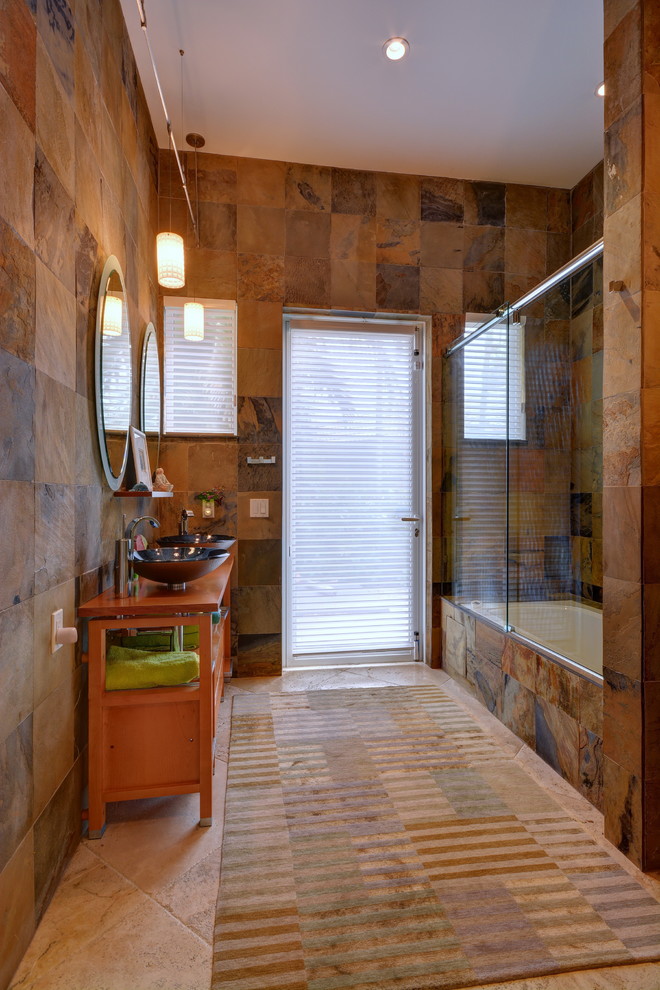 Esempio di una stanza da bagno stile americano di medie dimensioni con consolle stile comò, ante arancioni, vasca ad alcova, vasca/doccia, lavabo a bacinella, top in legno e porta doccia scorrevole