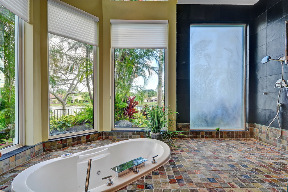 Diseño de cuarto de baño principal tropical con bañera encastrada, ducha abierta, baldosas y/o azulejos negros, paredes amarillas, suelo de pizarra, ducha abierta y baldosas y/o azulejos de pizarra