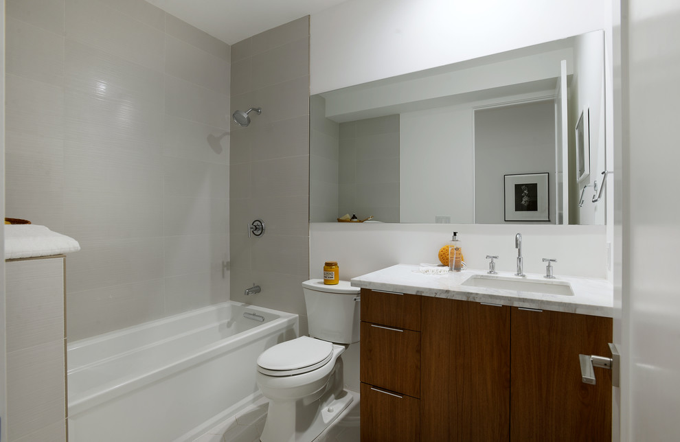 Idée de décoration pour une petite douche en alcôve principale en bois foncé avec un lavabo encastré, un placard à porte plane, un plan de toilette en marbre, une baignoire en alcôve, WC séparés et un mur blanc.
