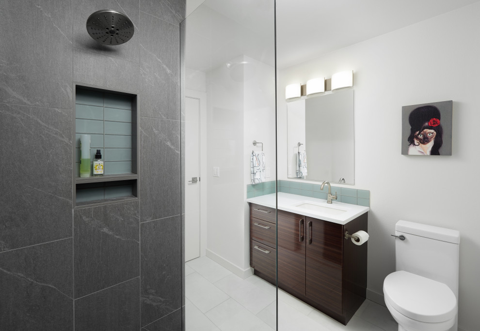 Design ideas for a medium sized contemporary ensuite bathroom in Portland with flat-panel cabinets, dark wood cabinets, an alcove shower, a two-piece toilet, blue tiles, glass tiles, white walls, porcelain flooring, a submerged sink, engineered stone worktops, white floors, a hinged door and white worktops.