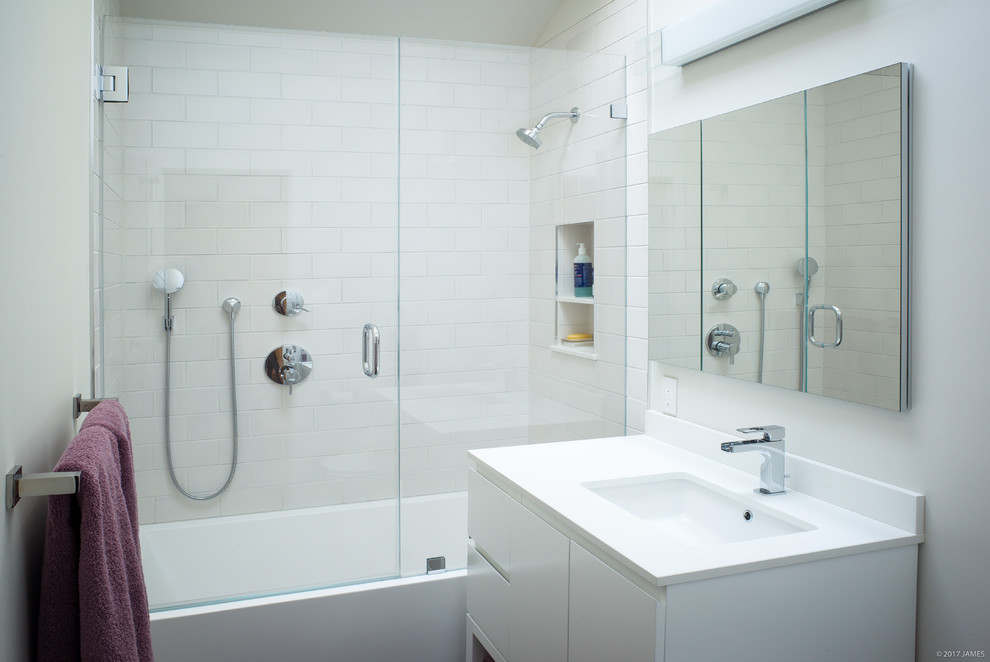 Photo of a small modern bathroom in Los Angeles with flat-panel cabinets, white cabinets, an alcove bath, a shower/bath combination, a one-piece toilet, white tiles, ceramic tiles, white walls, ceramic flooring, a submerged sink, engineered stone worktops, grey floors and a hinged door.
