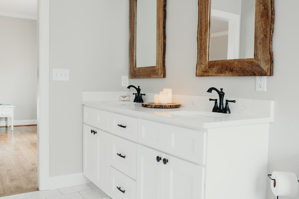 Inspiration for a medium sized rural ensuite bathroom in Charlotte with recessed-panel cabinets, white cabinets, white tiles, marble tiles, grey walls, a submerged sink, engineered stone worktops and white worktops.