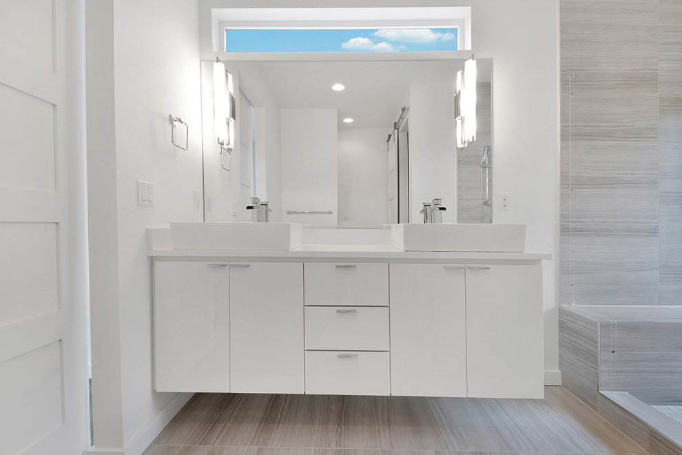 Cette photo montre une salle de bain principale moderne de taille moyenne avec une vasque, un placard à porte plane, des portes de placard blanches, un plan de toilette en quartz modifié, un carrelage gris, des carreaux de porcelaine, un mur blanc et un sol en carrelage de porcelaine.