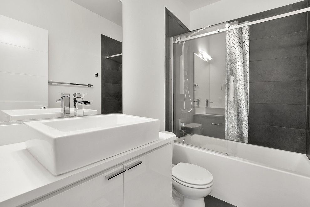 Exempel på ett mellanstort modernt badrum, med ett fristående handfat, släta luckor, vita skåp, bänkskiva i kvarts, ett badkar i en alkov, en dusch/badkar-kombination, grå kakel, porslinskakel, vita väggar och klinkergolv i porslin