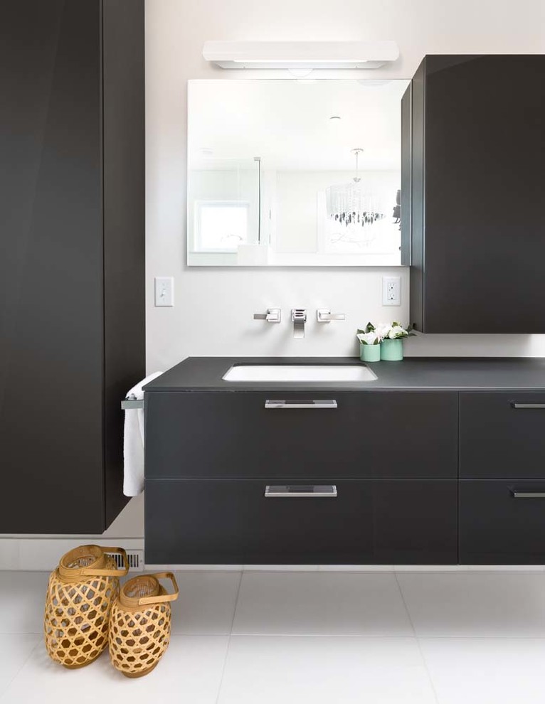 Réalisation d'une salle de bain principale design de taille moyenne avec un placard en trompe-l'oeil, des portes de placard grises, un plan de toilette en verre et un sol en bois brun.