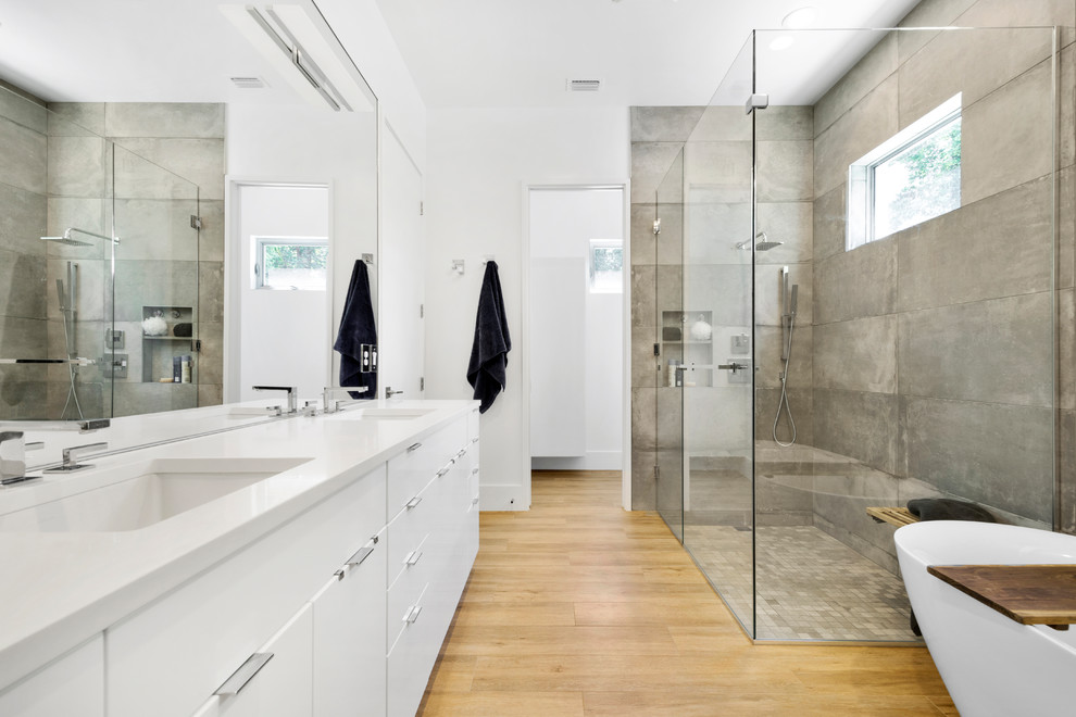 Inspiration för ett funkis en-suite badrum, med släta luckor, vita skåp, en kantlös dusch, grå kakel, vita väggar, ljust trägolv, ett undermonterad handfat, beiget golv och dusch med gångjärnsdörr