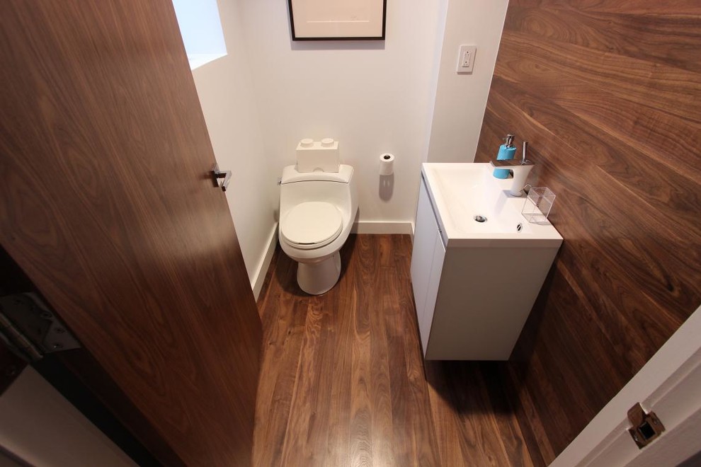 Modelo de cuarto de baño minimalista pequeño con armarios con paneles lisos, puertas de armario blancas, suelo de madera en tonos medios y aseo y ducha