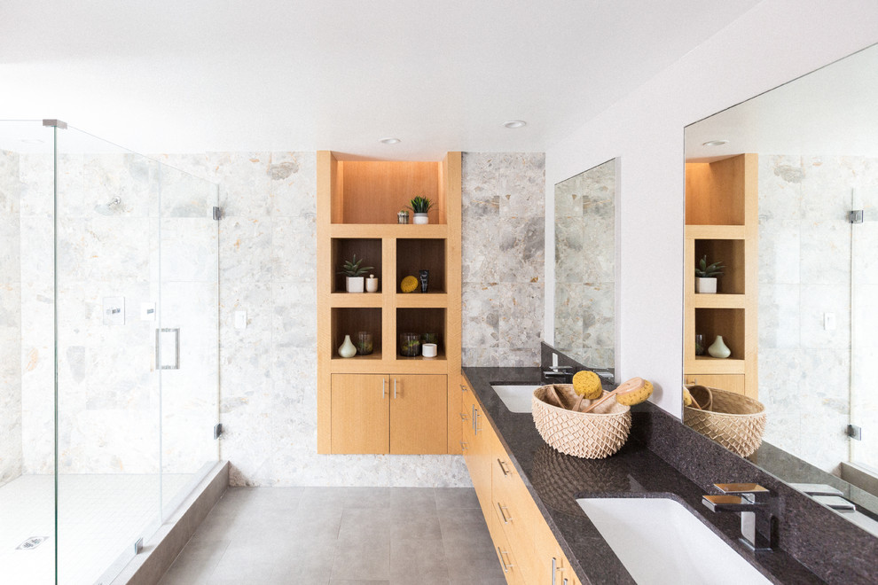 Cette photo montre une salle d'eau moderne en bois clair avec un placard à porte plane, une douche d'angle, un mur blanc, un lavabo encastré, un sol gris et une cabine de douche à porte battante.