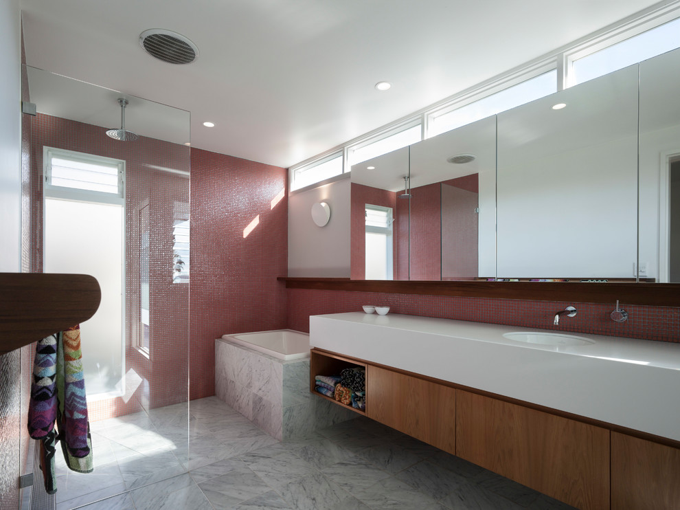 Inredning av ett modernt litet gul gult badrum med dusch, med släta luckor, bruna skåp, ett japanskt badkar, en öppen dusch, en vägghängd toalettstol, röd kakel, mosaik, grå väggar, marmorgolv, ett integrerad handfat, bänkskiva i akrylsten, grått golv och med dusch som är öppen
