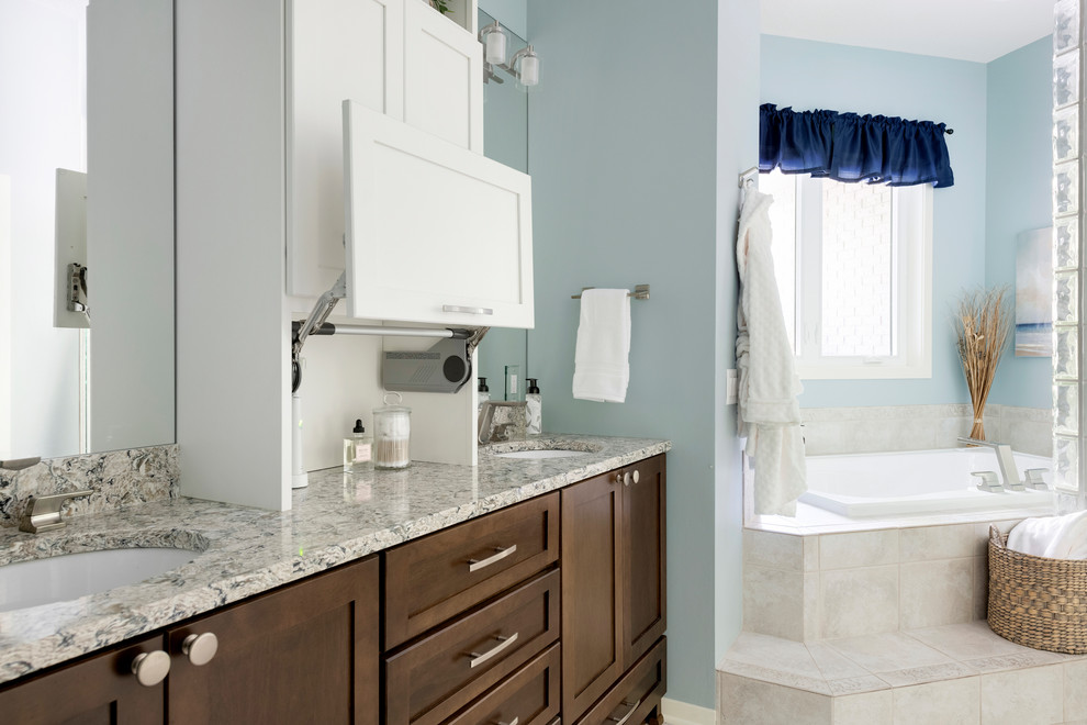 Photo of a large classic ensuite bathroom in Minneapolis with flat-panel cabinets, dark wood cabinets, a built-in bath, a double shower, a one-piece toilet, beige tiles, ceramic tiles, blue walls, ceramic flooring, a submerged sink, engineered stone worktops, beige floors, a hinged door and grey worktops.
