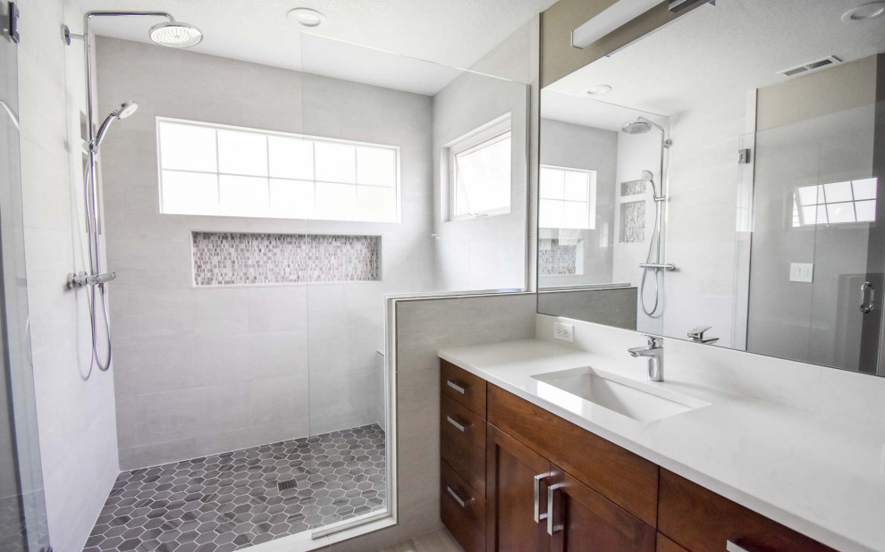 Inredning av ett modernt stort vit vitt en-suite badrum, med luckor med infälld panel, skåp i mellenmörkt trä, en dusch i en alkov, en toalettstol med separat cisternkåpa, grå kakel, keramikplattor, grå väggar, klinkergolv i keramik, ett undermonterad handfat, bänkskiva i kvarts, grått golv och dusch med gångjärnsdörr