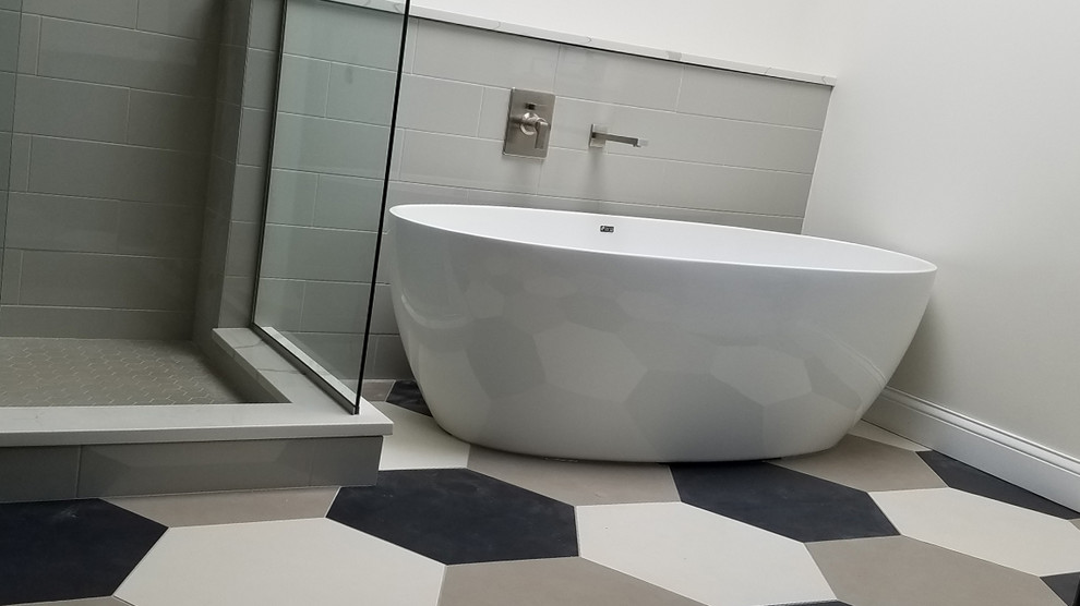 Inredning av ett modernt stort en-suite badrum, med grå skåp, ett fristående badkar, en dusch i en alkov, vit kakel, grå väggar, klinkergolv i porslin, ett undermonterad handfat, bänkskiva i kvarts, flerfärgat golv och dusch med gångjärnsdörr
