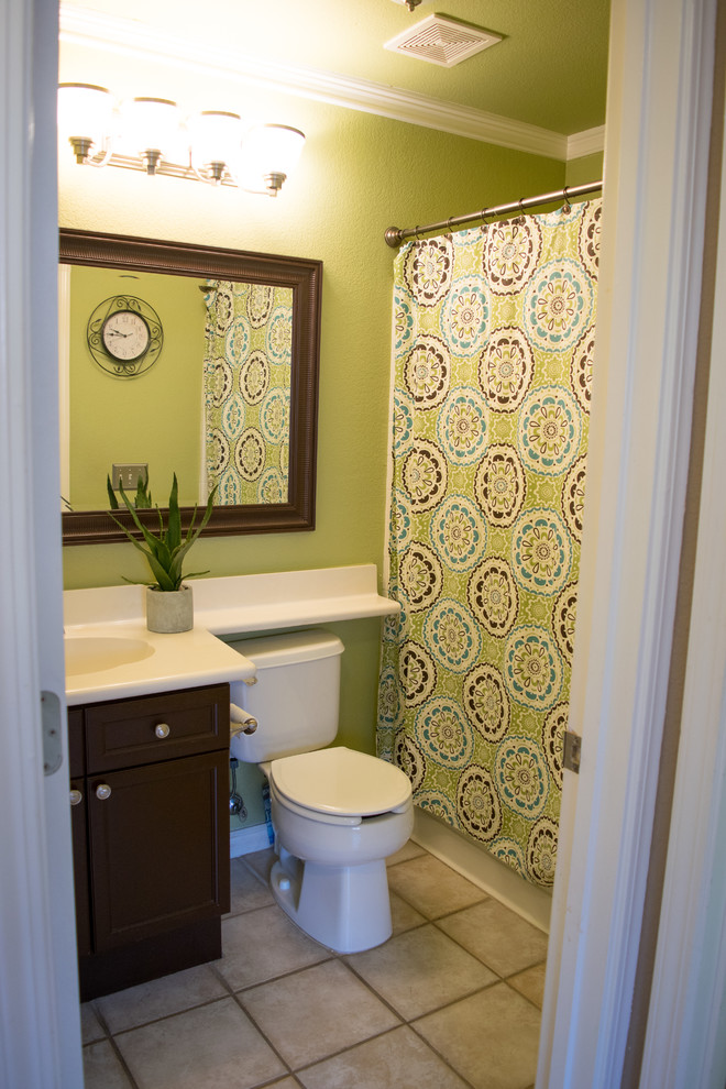 Klassisk inredning av ett litet badrum, med skåp i shakerstil, skåp i mörkt trä, ett badkar i en alkov, en dusch/badkar-kombination, en toalettstol med hel cisternkåpa, gröna väggar, ett integrerad handfat, beiget golv och dusch med duschdraperi