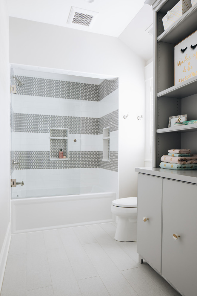 Bathroom - large transitional kids' gray tile and ceramic tile porcelain tile and gray floor bathroom idea in Chicago with flat-panel cabinets, gray cabinets, a two-piece toilet, gray walls, an undermount sink, quartz countertops, a hinged shower door and white countertops