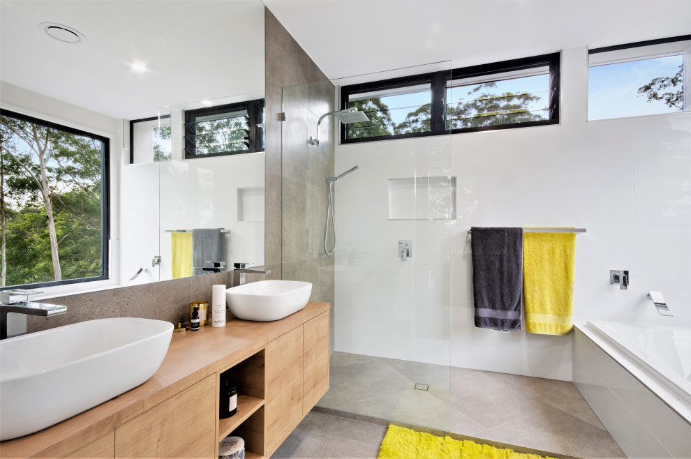 Medium sized contemporary ensuite bathroom in Sunshine Coast with light wood cabinets, a built-in bath, an alcove shower, a two-piece toilet, white tiles, ceramic tiles, grey walls, ceramic flooring, wooden worktops, grey floors, an open shower, double sinks, a floating vanity unit, a vessel sink, brown worktops and flat-panel cabinets.