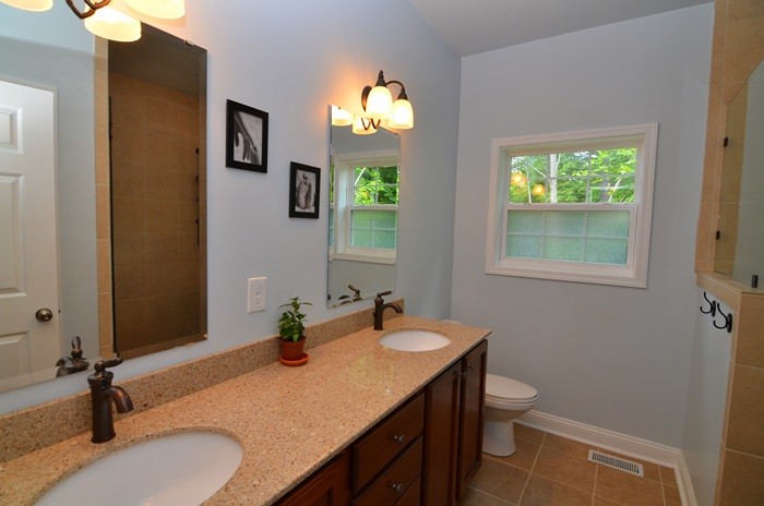 Immagine di una piccola stanza da bagno stile americano con top in marmo, WC monopezzo, piastrelle marroni, piastrelle in ceramica, pareti blu e pavimento con piastrelle in ceramica
