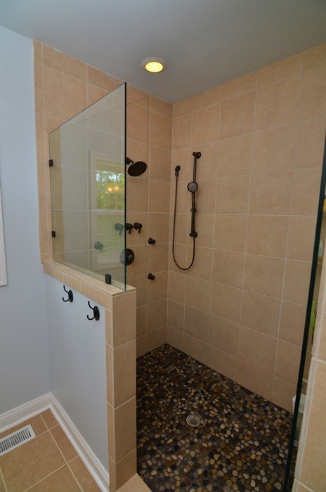 Amerikansk inredning av ett litet badrum, med marmorbänkskiva, en dusch i en alkov, en toalettstol med hel cisternkåpa, beige kakel, kakel i småsten, blå väggar och klinkergolv i keramik