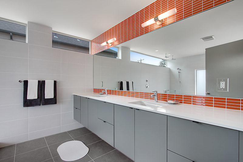 Diseño de cuarto de baño moderno con lavabo bajoencimera, armarios con paneles lisos, puertas de armario grises, encimera de cuarzo compacto, baldosas y/o azulejos naranja y baldosas y/o azulejos de vidrio