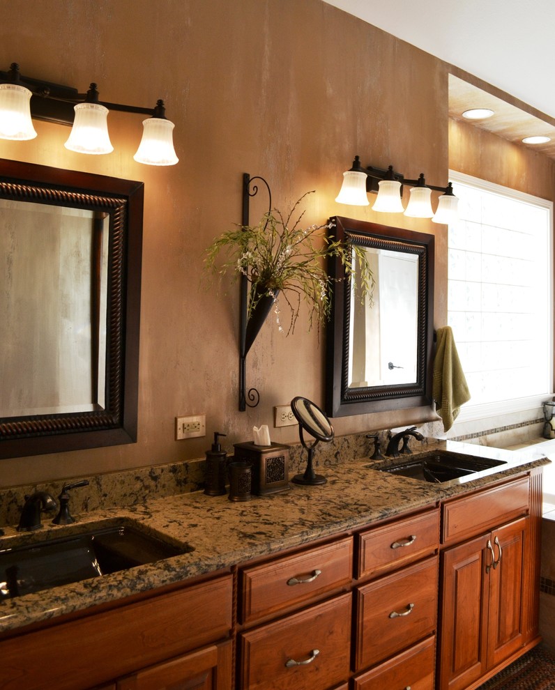 Exempel på ett klassiskt en-suite badrum, med ett undermonterad handfat, luckor med upphöjd panel, skåp i mellenmörkt trä, granitbänkskiva, ett hörnbadkar, en dusch i en alkov, flerfärgad kakel, stenkakel, bruna väggar och klinkergolv i porslin