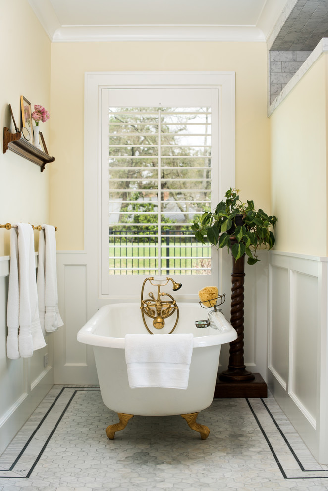 Mittelgroßes Klassisches Badezimmer En Suite mit Schrankfronten im Shaker-Stil, weißen Schränken, Löwenfuß-Badewanne, grauen Fliesen, gelber Wandfarbe und weißem Boden in Houston