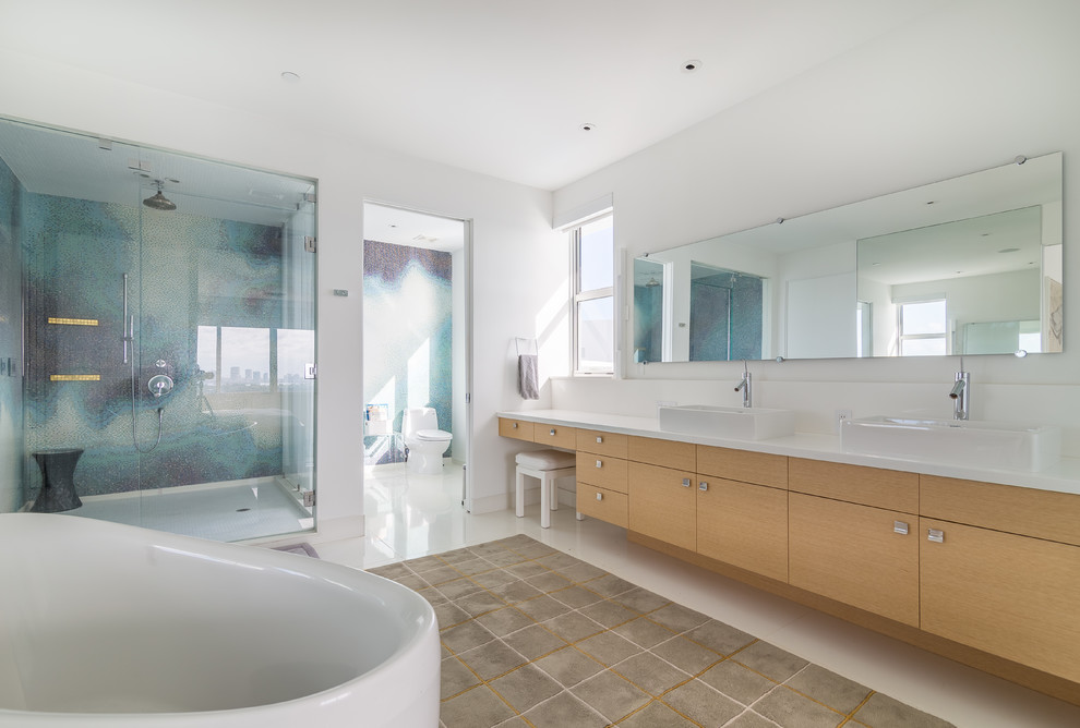 Immagine di una grande stanza da bagno padronale minimal con lavabo integrato, ante lisce, ante in legno chiaro, vasca freestanding, doccia ad angolo, WC monopezzo, piastrelle bianche e pareti bianche