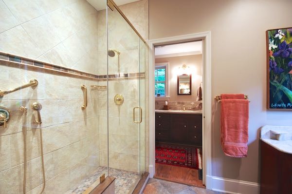 Cette photo montre une douche en alcôve principale chic en bois foncé de taille moyenne avec un lavabo intégré, un placard à porte affleurante, un plan de toilette en surface solide, un carrelage multicolore, un carrelage de pierre, un mur beige et un sol en bois brun.