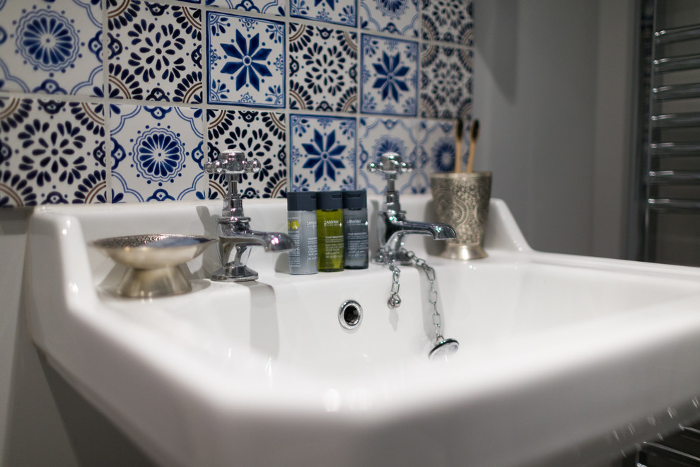 Immagine di una stanza da bagno con doccia mediterranea di medie dimensioni con doccia ad angolo, WC a due pezzi, piastrelle blu, piastrelle in ceramica, pareti grigie, pavimento in linoleum e lavabo a colonna