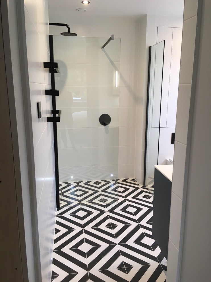 Small modern ensuite bathroom in Other with flat-panel cabinets, blue cabinets, a walk-in shower, a one-piece toilet, white tiles, ceramic tiles, white walls, porcelain flooring, a vessel sink, quartz worktops, black floors, an open shower and white worktops.