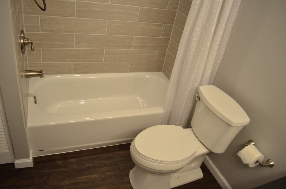 Bild på ett mellanstort funkis badrum, med ett undermonterad handfat, luckor med upphöjd panel, vita skåp, granitbänkskiva, ett badkar i en alkov, en dusch/badkar-kombination, en toalettstol med separat cisternkåpa, beige kakel, porslinskakel, grå väggar och linoleumgolv