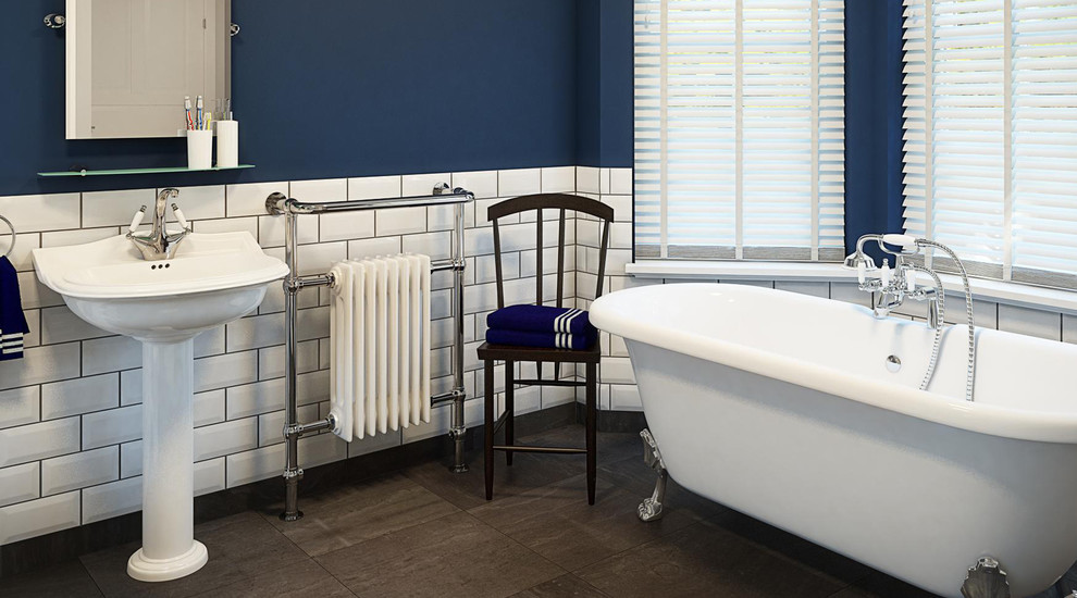 Ispirazione per una grande stanza da bagno classica con lavabo sospeso, vasca con piedi a zampa di leone, piastrelle bianche, pareti blu e parquet scuro