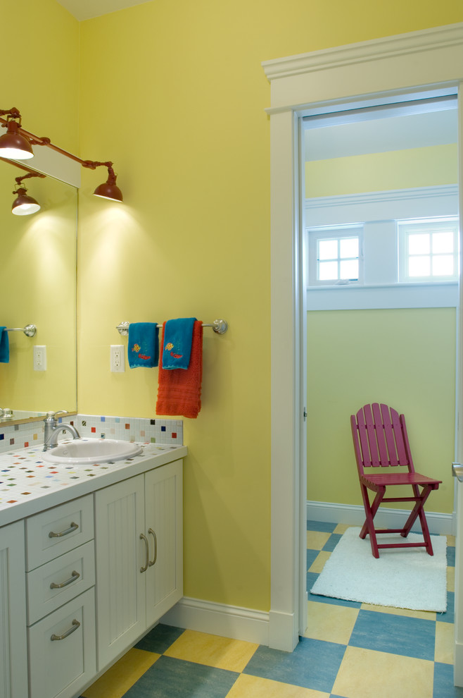 На фото: детская ванная комната в морском стиле с накладной раковиной, фасадами с утопленной филенкой, белыми фасадами, столешницей из плитки, душем над ванной, разноцветной плиткой, керамической плиткой, желтыми стенами и разноцветной столешницей с