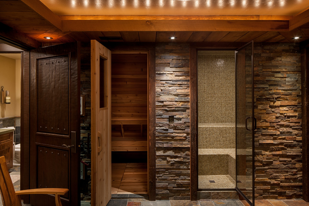 Exemple d'un grand sauna montagne en bois foncé avec un espace douche bain, un mur marron, un sol en ardoise, un sol multicolore, aucune cabine, une baignoire sur pieds, un lavabo encastré et un mur en pierre.