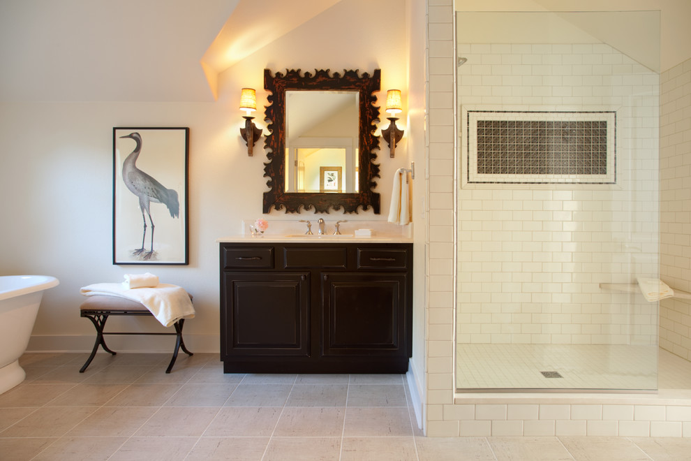 Klassisk inredning av ett badrum, med ett fristående badkar, tunnelbanekakel, ett undermonterad handfat, skåp i mörkt trä, en dusch i en alkov och vit kakel