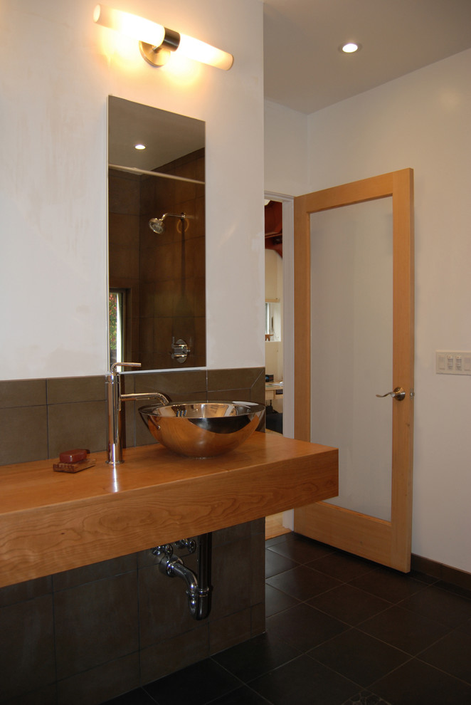 Modern inredning av ett badrum, med ett fristående handfat och träbänkskiva